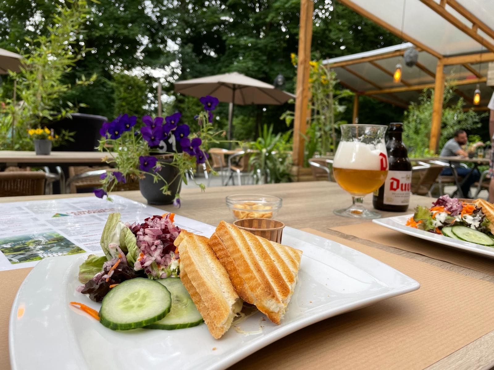 Een crocque monsieur met een slaatje en een glas duvel op een houten tafel in Durbuy