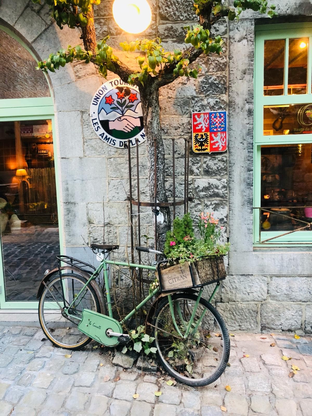 een oude groene fiets voor een stenen muur in centrum Durbuy