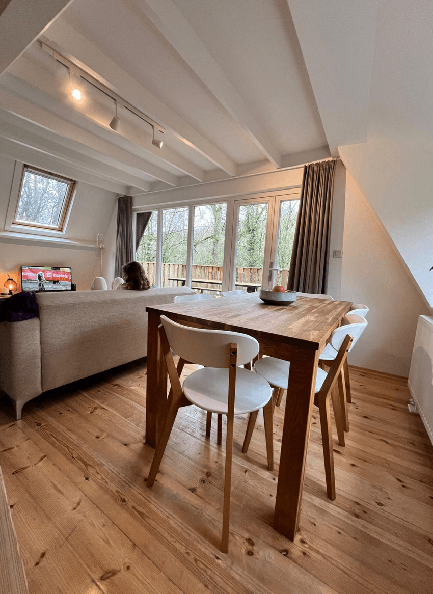 Een houten tafel met witte stoelen in een verlicht huisje in Sunclass Durbuy